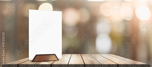 Menu with isolated white on wooden table on blurred coffee shop background