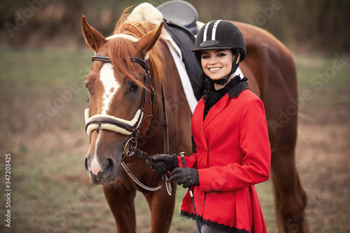 Beautiful woman jockey rider with brown horse outdoors
