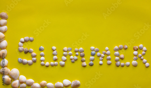 Inscription of the word Summer by seashells on a yellow background. The vacation, recreation, travel concept 