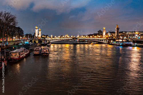 beautiful urban landscape of the seine river bordered the city of paris  in the river you can see some boats that make a house  a bridge in the distance and a sky with blue color and clouds