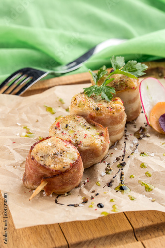 Bacon Wrapped Pork Medallions on wooden board on green background