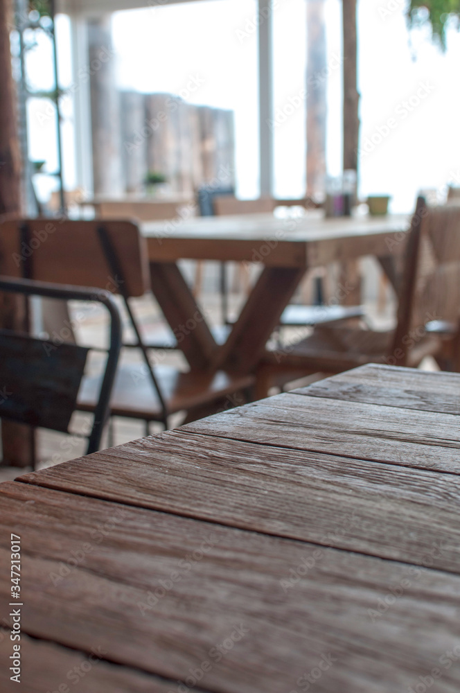 Obraz premium A used wooden table in the foreground, sharply focused. In the background there are more tables and chairs from the beach bar in the Netherlands. A cozy, picturesque location.