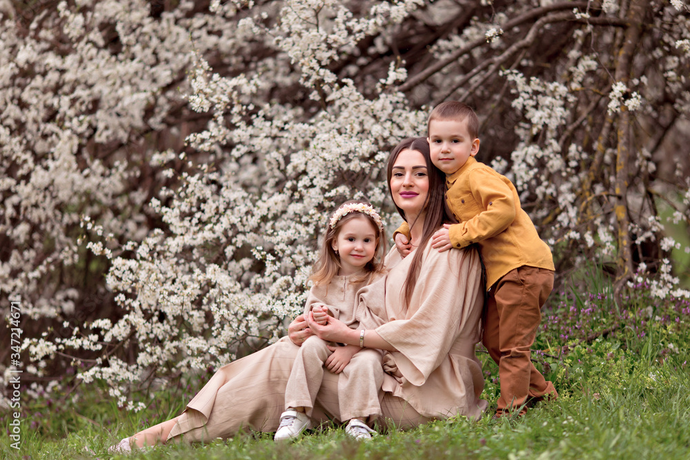 Happy family, a young mother waiting for the baby, daughter and son in the fresh spring air on a background of flowering trees. Happy family, a young mother waiting for the baby, daughter and son in the fresh spring air on a background of flowering trees.