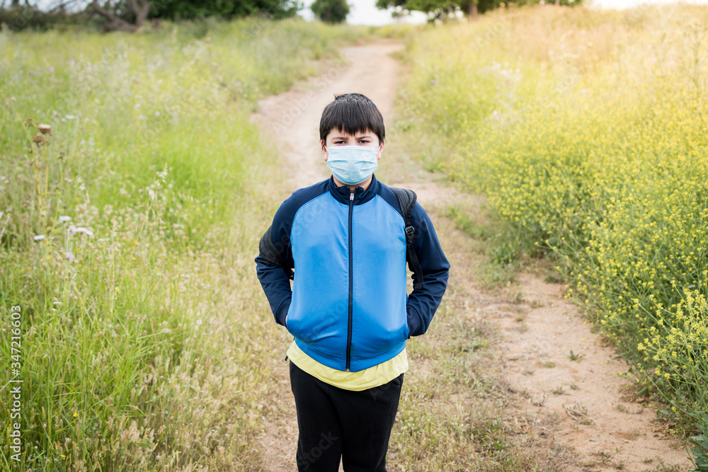 Naklejka premium Boy with backpack and blue jacket prepared to go to school with the mask on his face.