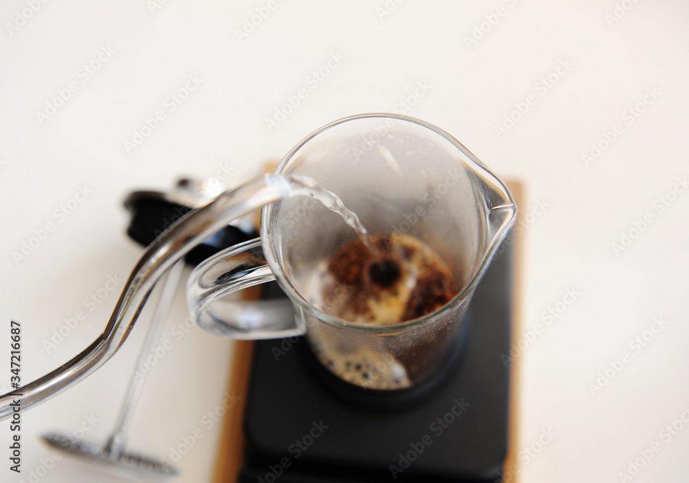 Fototapeta premium Brewing coffee in french press. Pouring hot water close up. Top view. White background