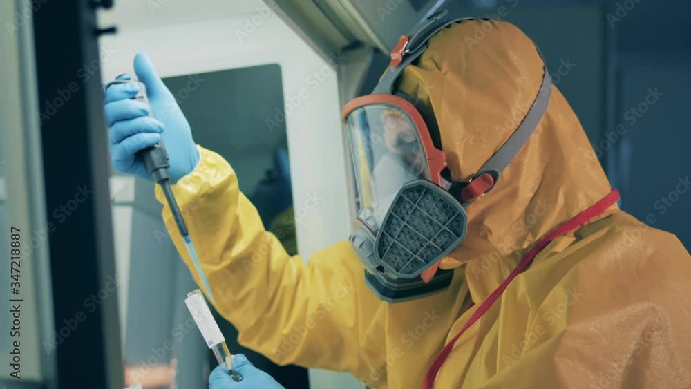 Expert in a hazmat suit is analyzing biological substance Expert in a hazmat suit is analyzing biological substance