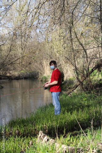 a masked man on a river fishing during quarantine, a violation of self-isolation during the coronavirus pandemic