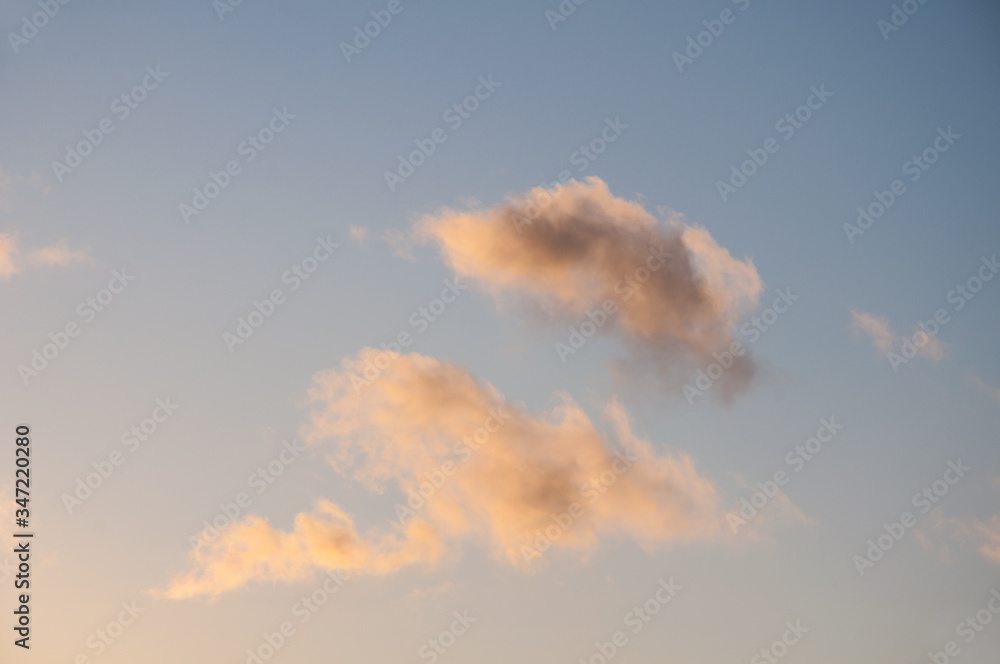 Clouds at sunrise in shades of pink and orange against the blue sky.  Weather and environment nature great for backgrounds too.