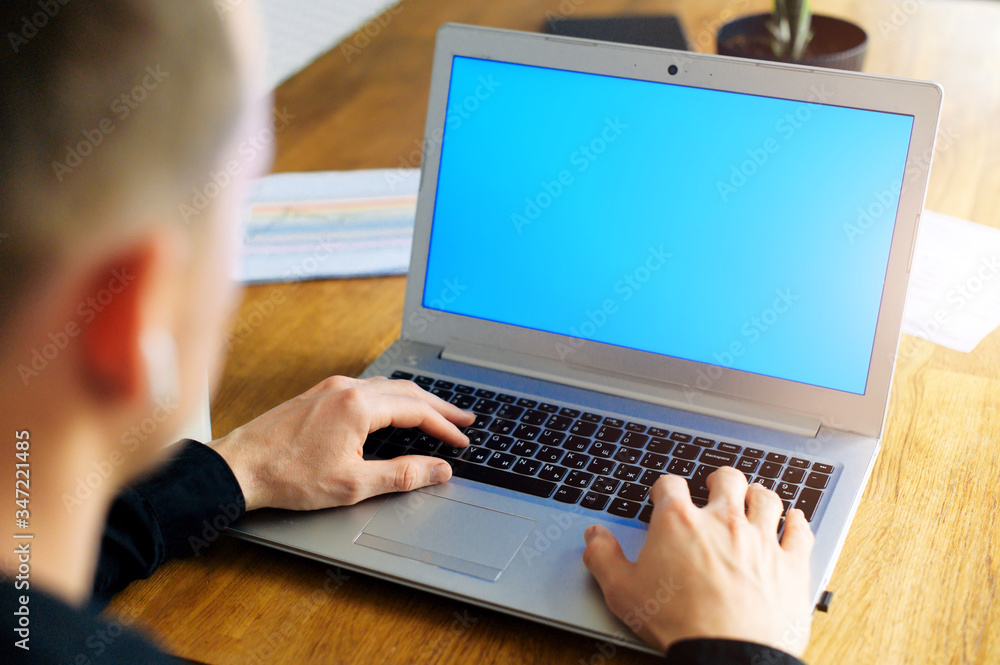 Man is typing on keyboard of laptop with blank screen. Rear view. Copyspace for text Man is typing on keyboard of laptop with blank screen. Rear view. Copyspace for text