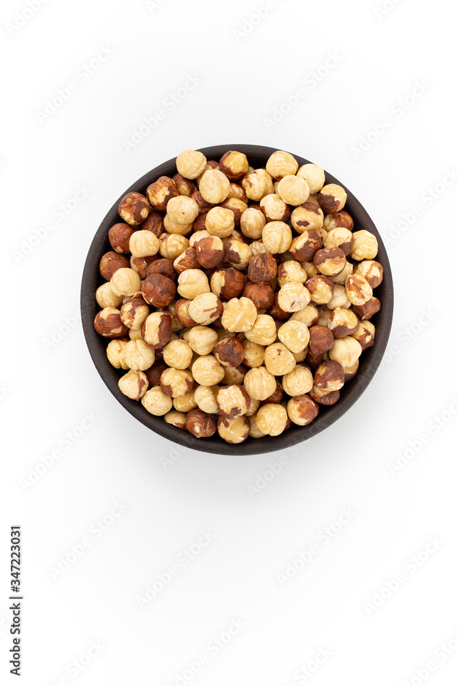 Roasted cleaned hazelnuts in round bowl on white background, top view Roasted cleaned hazelnuts in round bowl on white background, top view