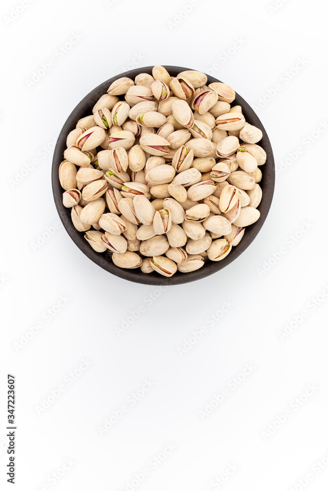 Roasted salty Pistachios in round bowl on white background, top view Roasted salty Pistachios in round bowl on white background, top view