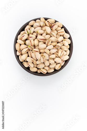 Roasted salty Pistachios  in round bowl on white background, top view