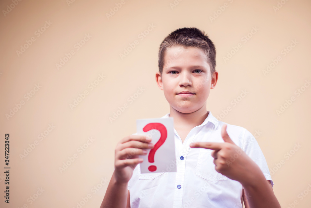 A portrait of kid boy holding cards with question mark. Childhood and education concept A portrait of kid boy holding cards with question mark. Childhood and education concept