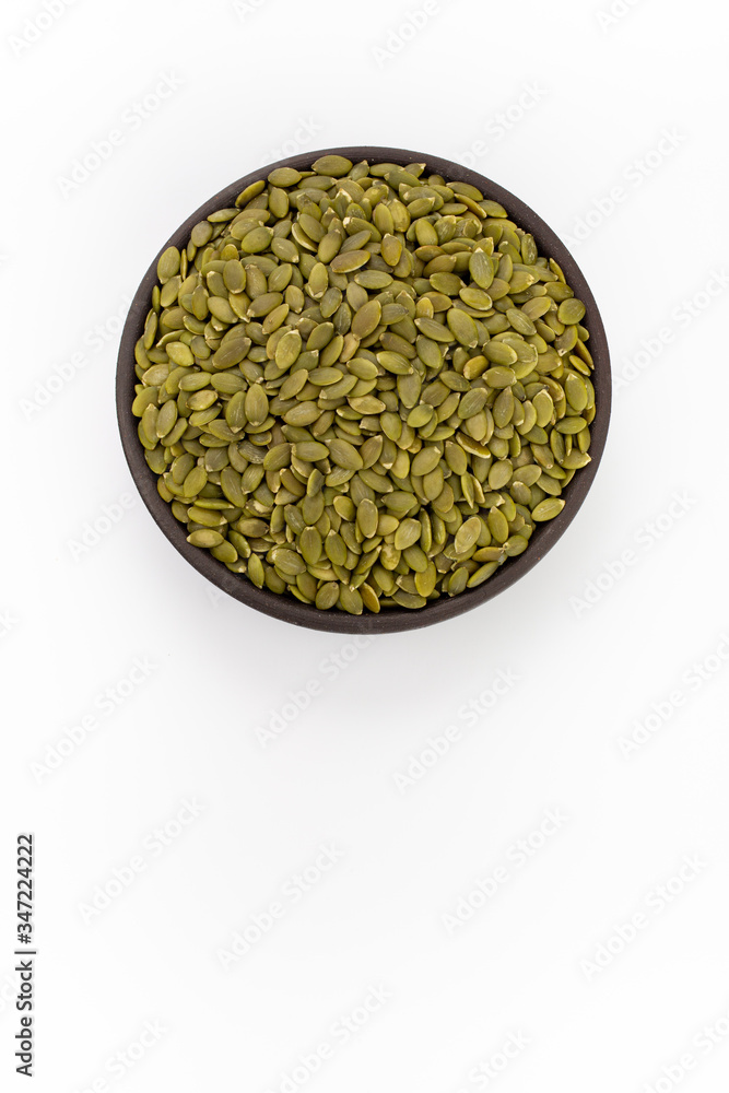 Pumpkin seeds in round bowl on white background, top view Pumpkin seeds in round bowl on white background, top view