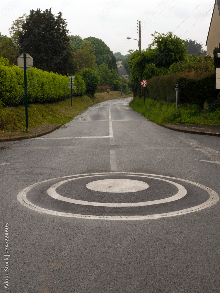 A small intersection roundabout point and an empty road running down and curving. A small intersection roundabout point and an empty road running down and curving.