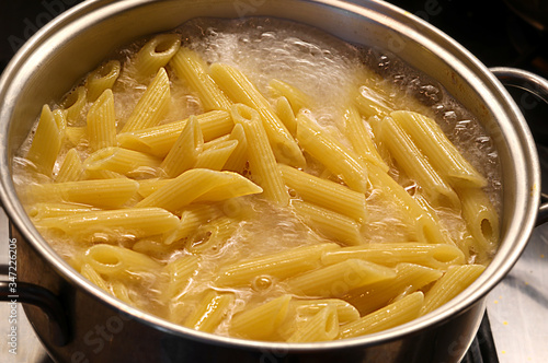 pot with boiling water and Italian pasta during cooking photo