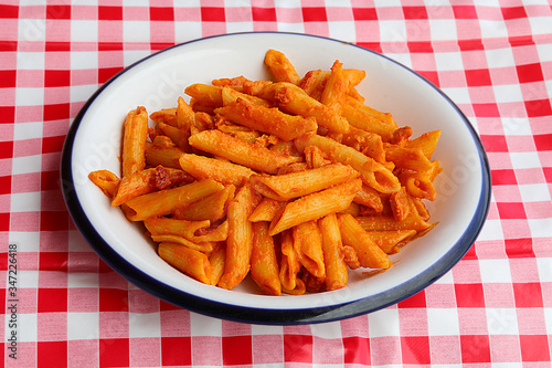 pasta with tomato and cheese on a red and white checkered tablec