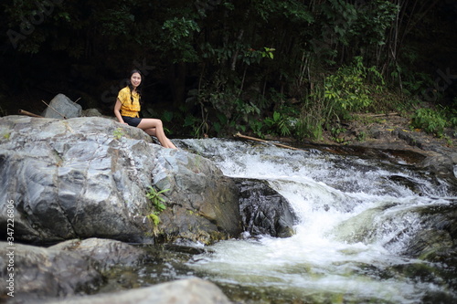 Fototapeta Naklejka Na Ścianę i Meble -  Woman sitting at Khlong Nam Lai waterfall in Klong Lan national park, Kamphaeng Phet, Thailand