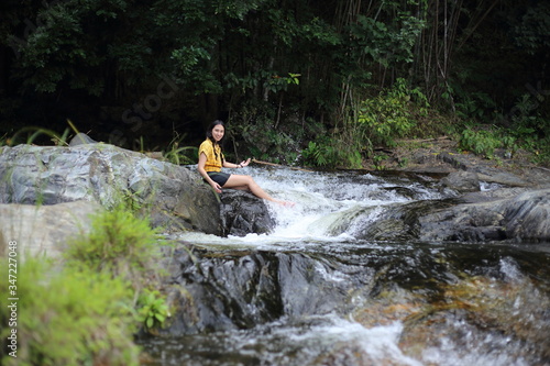 Fototapeta Naklejka Na Ścianę i Meble -  Woman sitting at Khlong Nam Lai waterfall in Klong Lan national park, Kamphaeng Phet, Thailand