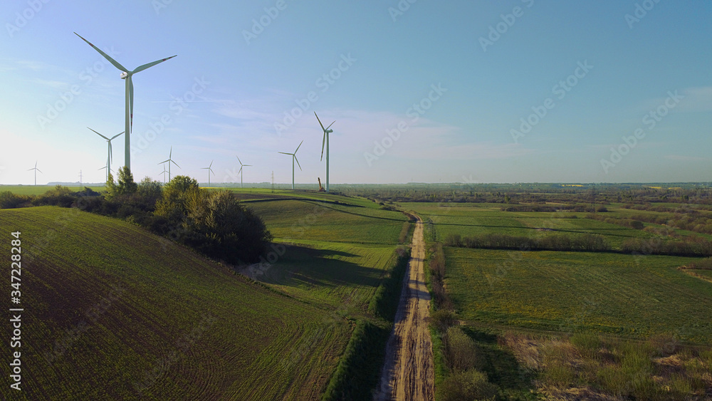 Fototapeta premium Wind farm towers surrounded by agricultural fields in Polish country side. Pomerania, Poland.