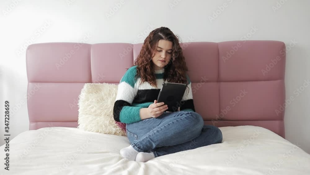 Gorgeous woman using a tablet computer in her bedroom. Beautiful pregnant young woman using digital tablet and smiling in bed. Woman watch on tablet computer on bed. Gorgeous woman using a tablet computer in her bedroom. Beautiful pregnant young woman using digital tablet and smiling in bed. Woman watch on tablet computer on bed.
