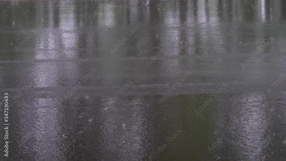 Spring heavy rain, raindrops fall on the road covered with black asphalt, car wheels pass splashing water and leaving traces on the asphalt, slow motion Spring heavy rain, raindrops fall on the road covered with black asphalt, car wheels pass splashing water and leaving traces on the asphalt, slow motion
