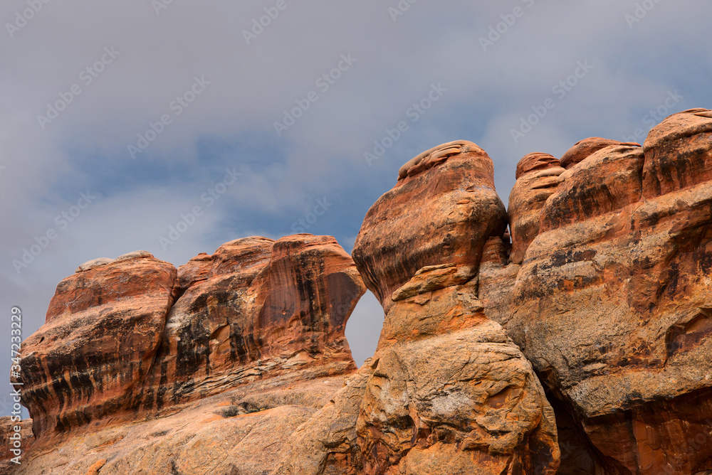Rounded red cliffs on a background of cloudy sky in Arches National Park.