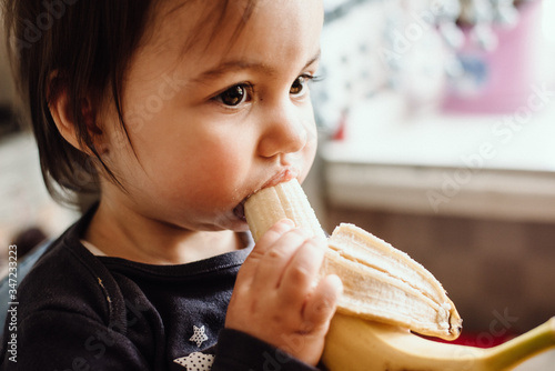 Cute baby eating banana. Cute little girl eating fruit. Healthy snack  food