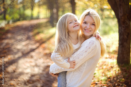 Beautiful, happy young mother with little daughter playing in Autumn park.