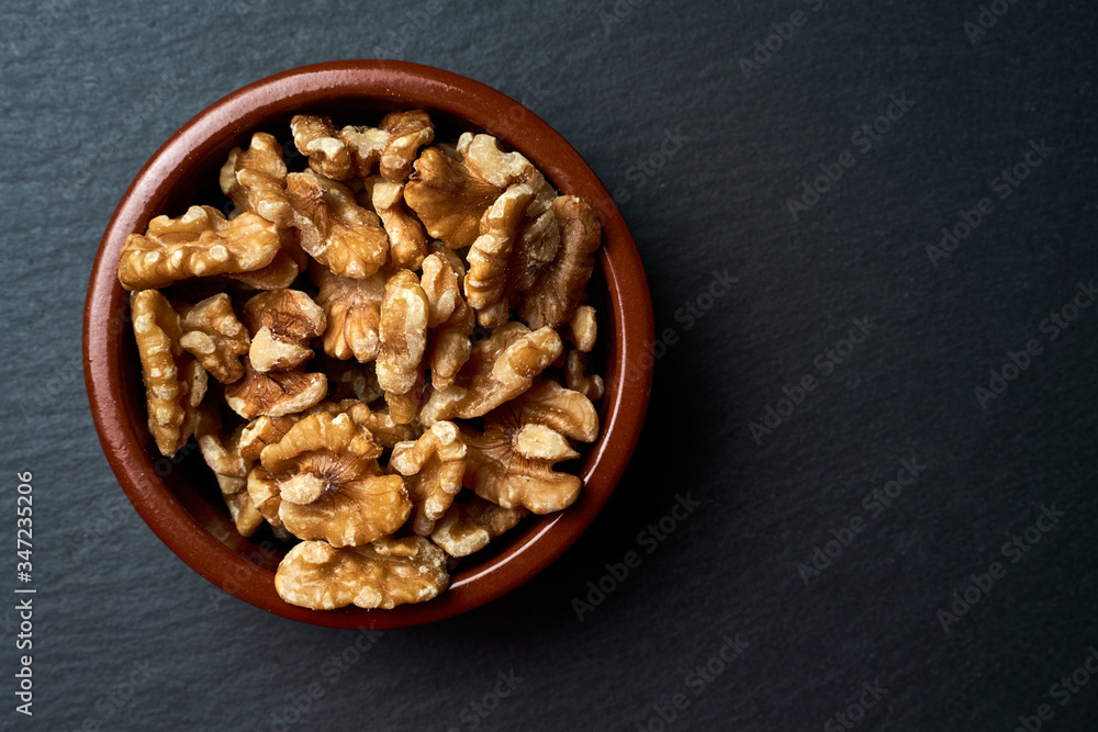 Ceramic bowl with peeled nuts on a dark background. Ceramic bowl with peeled nuts on a dark background.