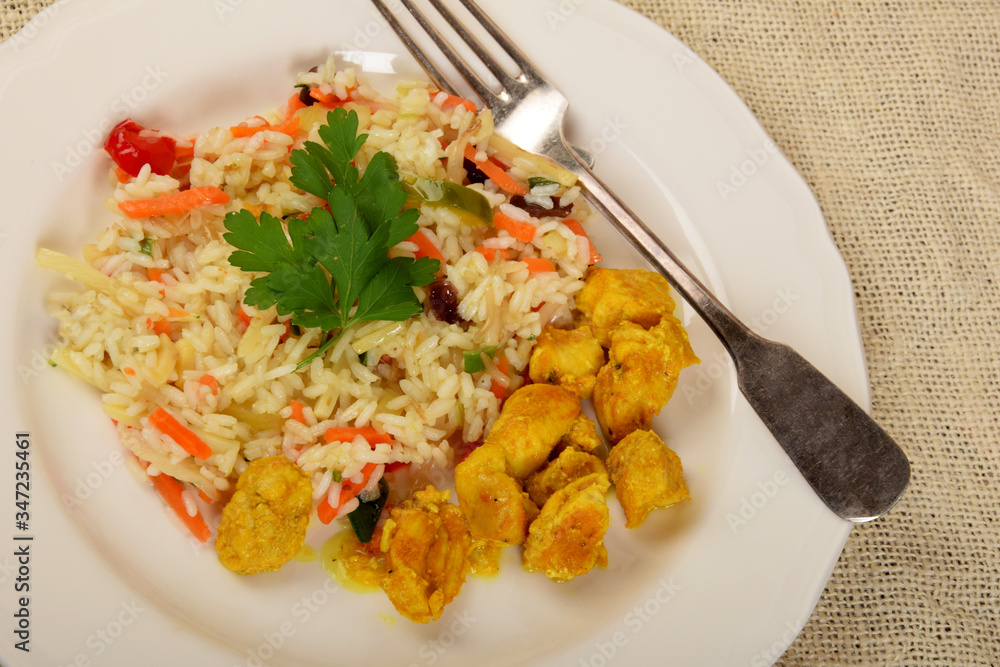 pieces of fried chicken in curry with rice and vegetables on a white plate pieces of fried chicken in curry with rice and vegetables on a white plate