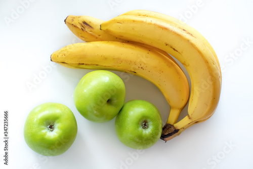 Bananas and green apples on a white isolated background.Top view