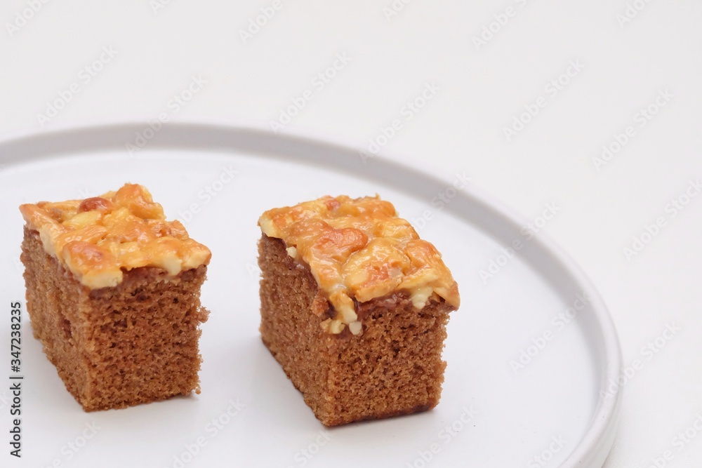 Close up a pair of toffee cake pieces on a plate with white background 