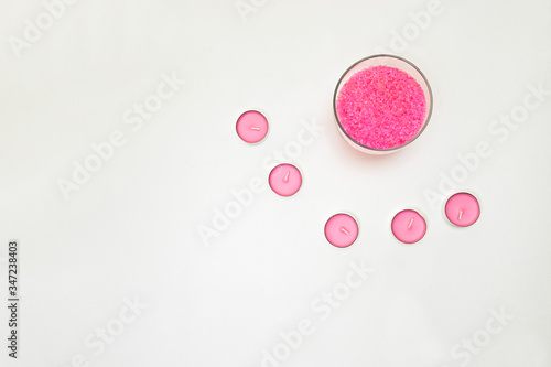 Light pink candles stand in a circle around the bath salt. Items for spa treatments .Gentle colors. Horizontal photo. Space for text.