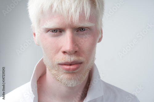 portrait of an albino man in studio dressed t-shirt isolated on a white background. abnormal deviations. unusual appearance photo