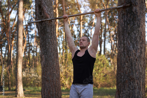 Handsome caucasian men pull-up outdoor workout cross training morning Pumping up arm exercising sports ground nature forest © Andrii