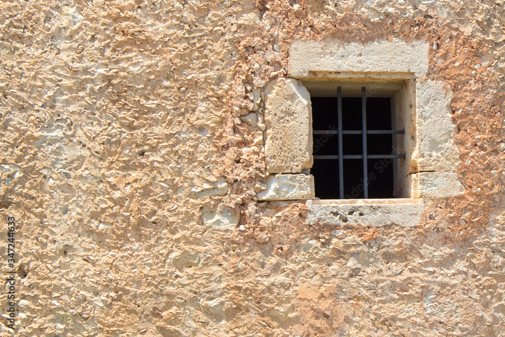 a window with bars on an old wall