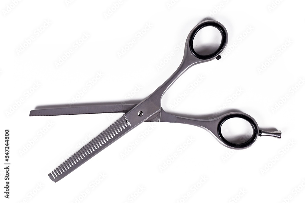 Thinning shears, a pair of hair scissors with blades with teeth on the edge like a comb used to reduce hair thickness or blend layered hair on white background Thinning shears, a pair of hair scissors with blades with teeth on the edge like a comb used to reduce hair thickness or blend layered hair on white background