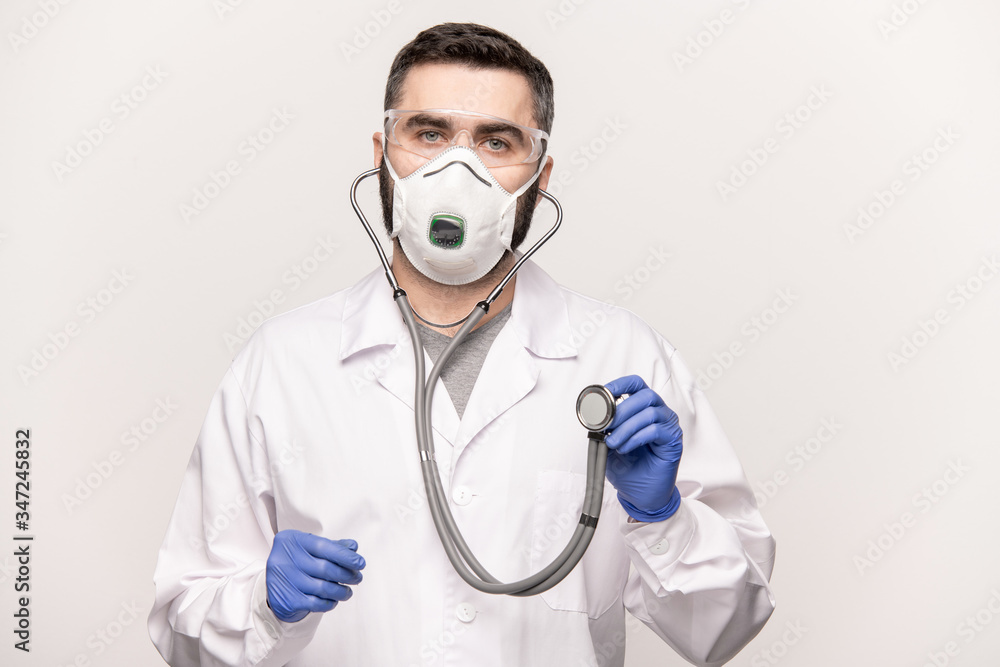 Young male clinician in uniform holding stethoscope during medical examination Young male clinician in uniform holding stethoscope during medical examination