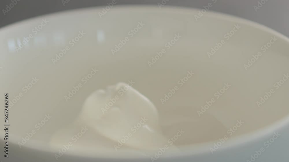 Slow motion natural yogurt fall into white bowl closeup Slow motion natural yogurt fall into white bowl closeup