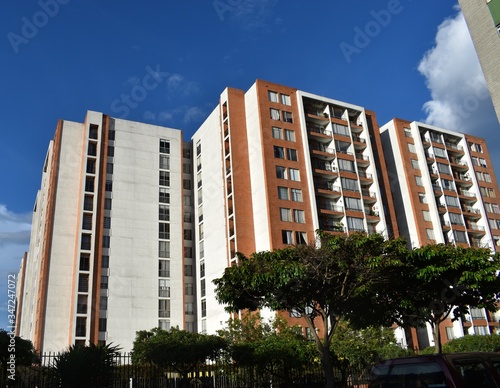Panorámicas tres torres de edificios residenciales, rodeados de árboles, en una mañana de cielo despejado.