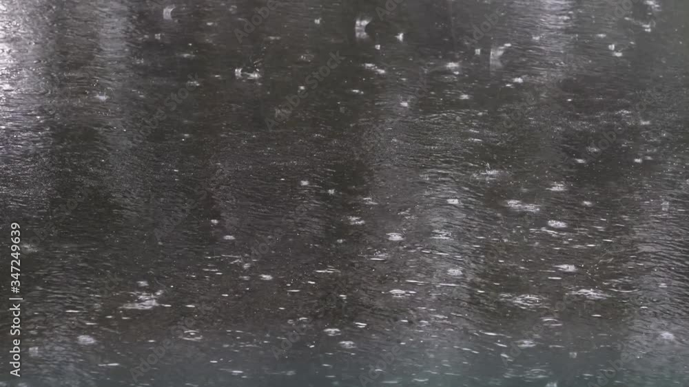 Spring heavy rain, raindrops fall on the road covered with black asphalt, car wheels pass splashing water and leaving traces on the asphalt Spring heavy rain, raindrops fall on the road covered with black asphalt, car wheels pass splashing water and leaving traces on the asphalt
