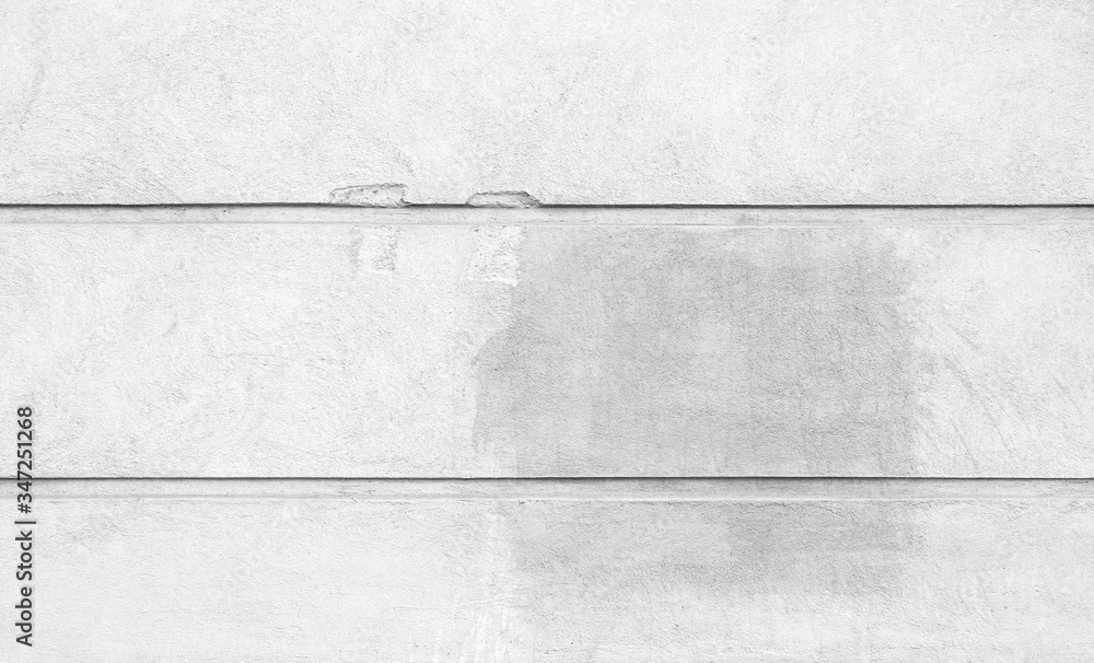 Front view of a plastered and damaged gray stone wall with stains from graffiti removal. Abstract high resolution full frame textured background in black and white. Front view of a plastered and damaged gray stone wall with stains from graffiti removal. Abstract high resolution full frame textured background in black and white.
