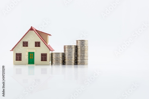 Home or residentail house model and stacks of rising coins.