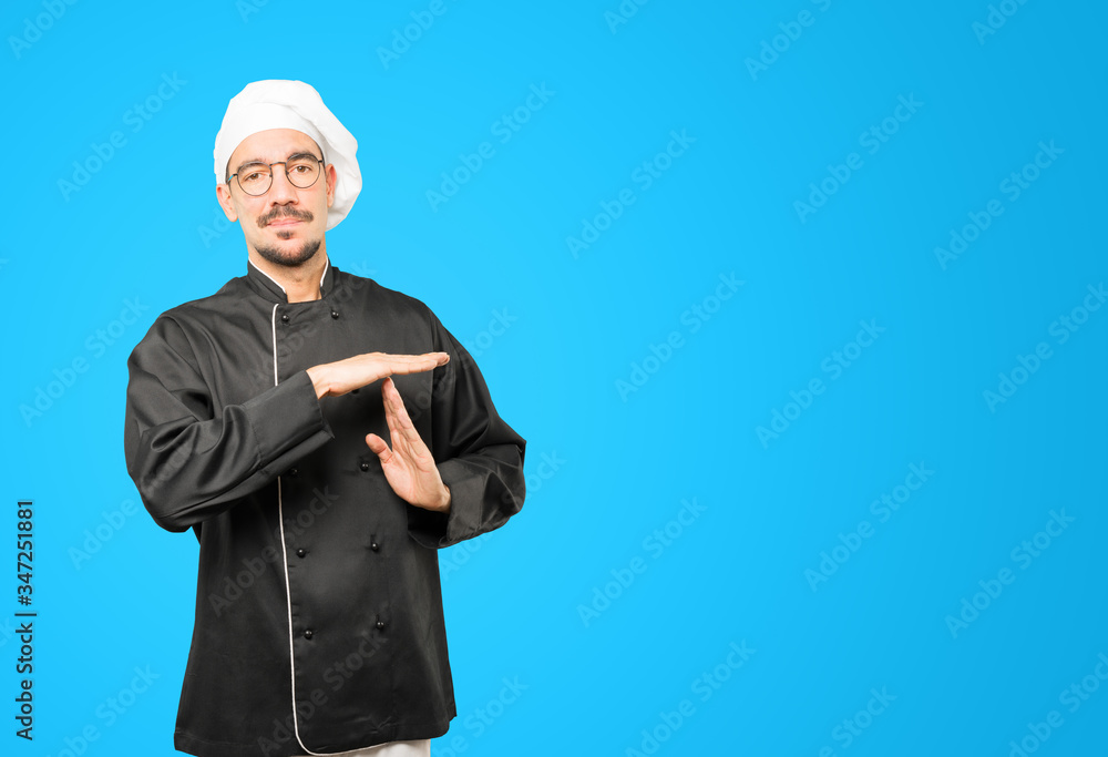 Stressed young chef making a time out gesture with his hands Stressed young chef making a time out gesture with his hands