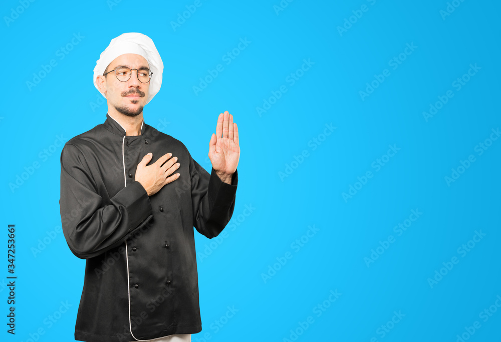 Serious young chef with a gesture of oath Serious young chef with a gesture of oath