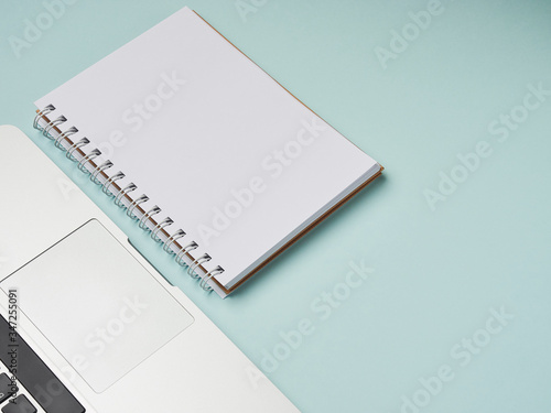 Open laptop with white notepad on a blue background. place for text. freelance, remote work