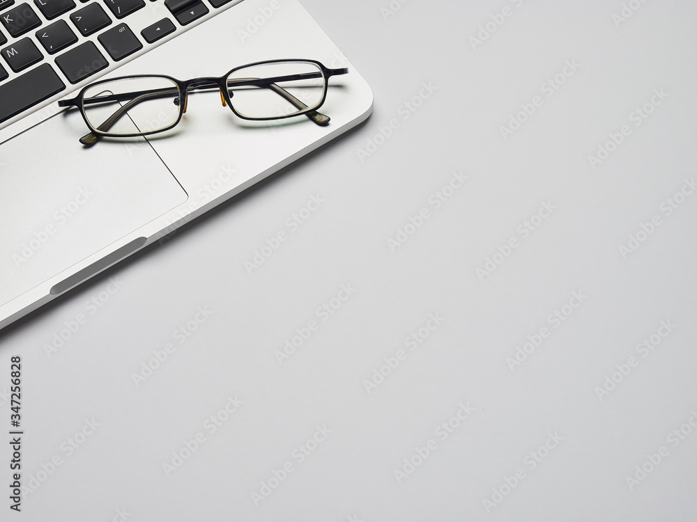 Workplace - laptop and glasses for remote work on a gray background table. Freelance desktop for home or office. Background with copy space. Workplace - laptop and glasses for remote work on a gray background table. Freelance desktop for home or office. Background with copy space.