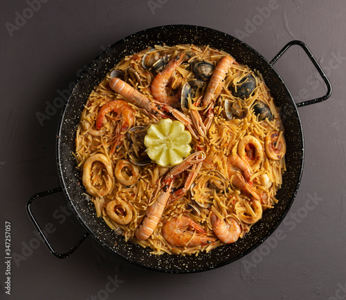 seafood fideua black background traditional food, top view photo