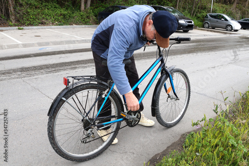 man straightens a chain on a bicycle 